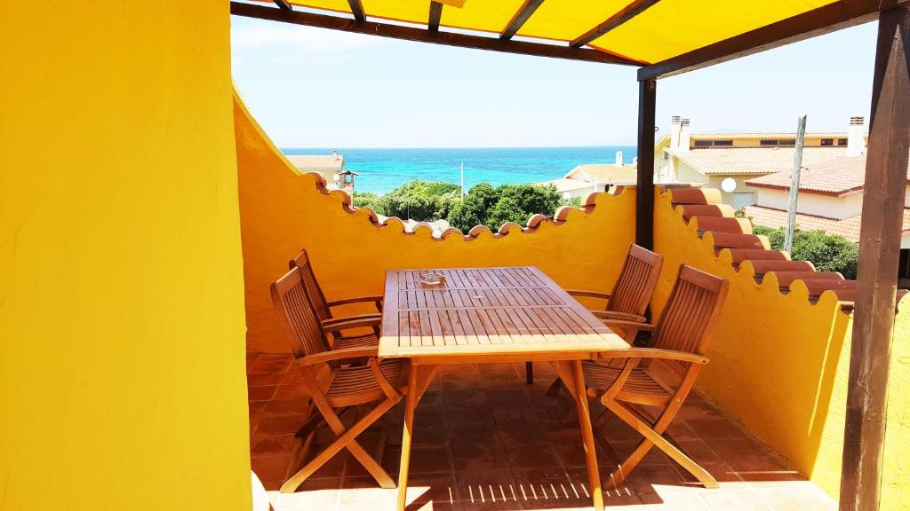 einen Tisch und Stühle auf einem Balkon mit Meerblick in der Unterkunft La Baia Apartments in Putzu Idu