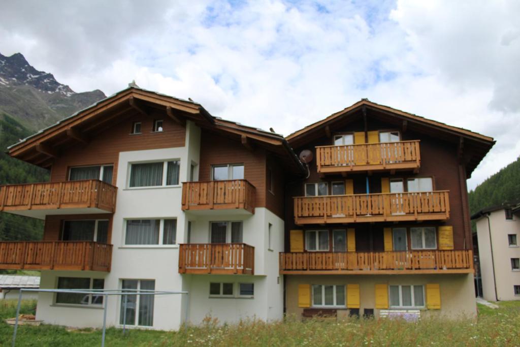 an apartment building with wooden balconies and mountains at Haus Weideli, Dammstrasse 7 in Saas-Grund
