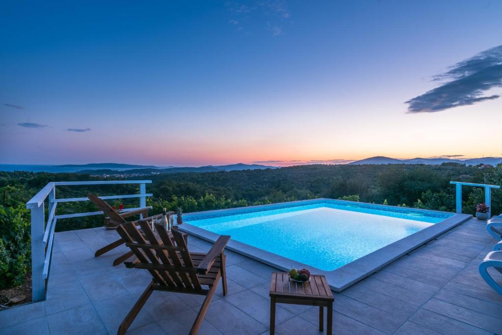 a villa with a swimming pool and two chairs at Villa Andante in Trogir