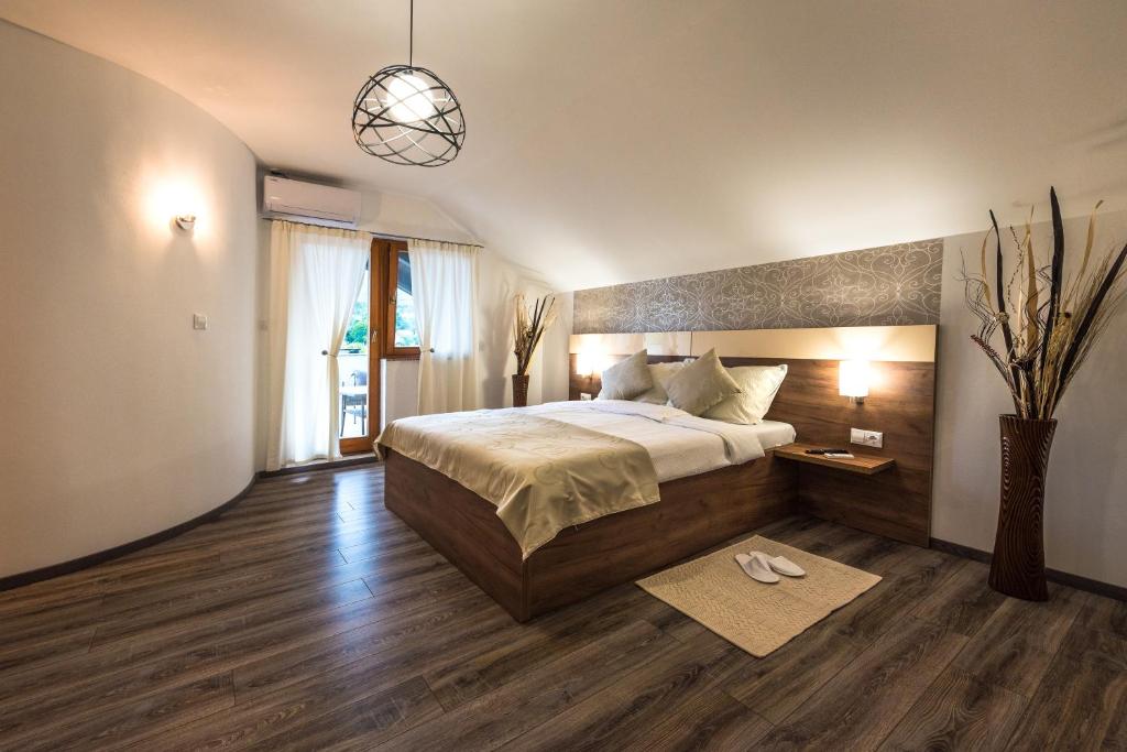 a bedroom with a large bed and a pendant light at Guest House Vana in Korenica