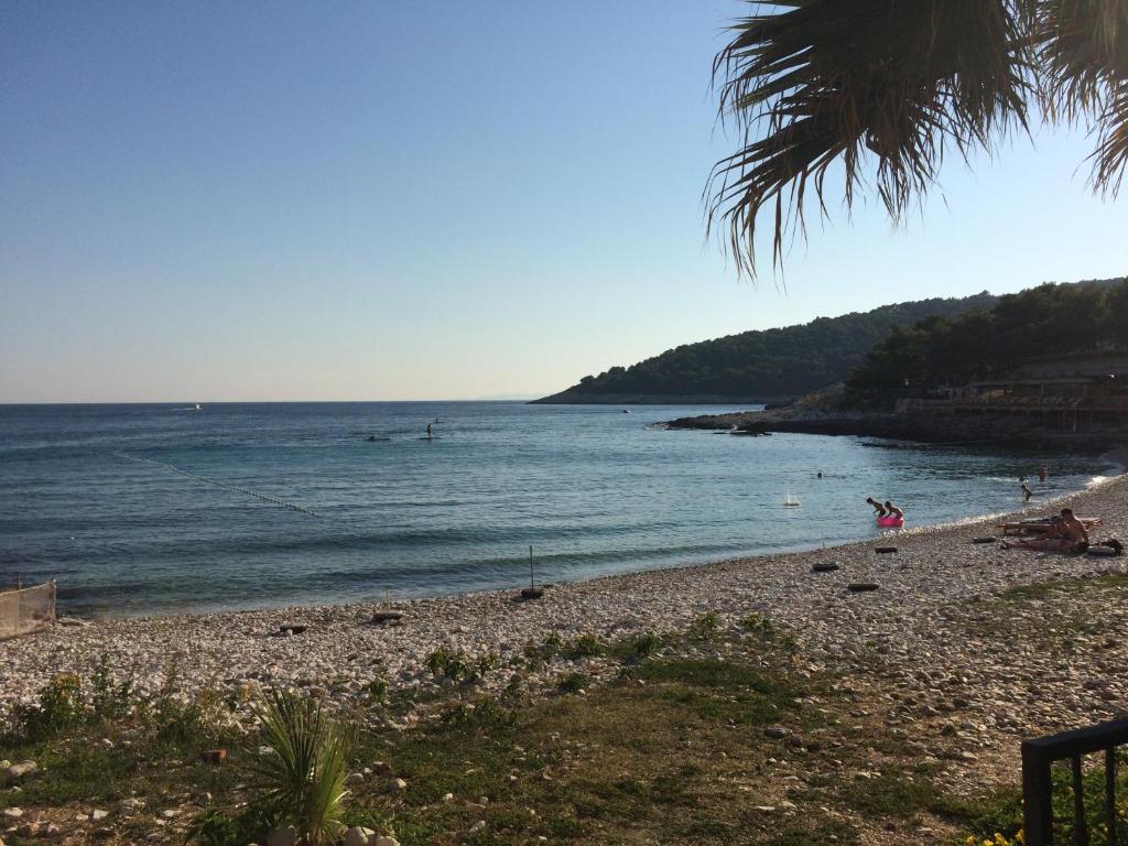 een strand met mensen die in het water zwemmen bij Apartmani Kronjac in Milna