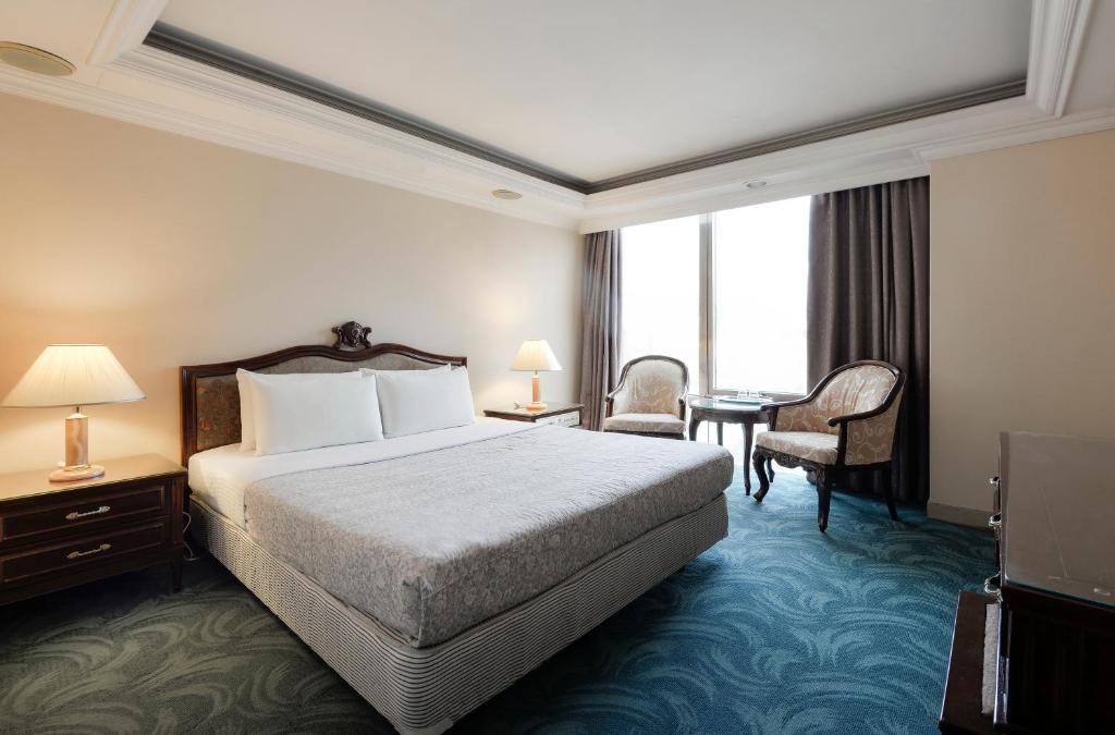 a hotel room with a bed and a desk at Forbes Hotel in Taichung