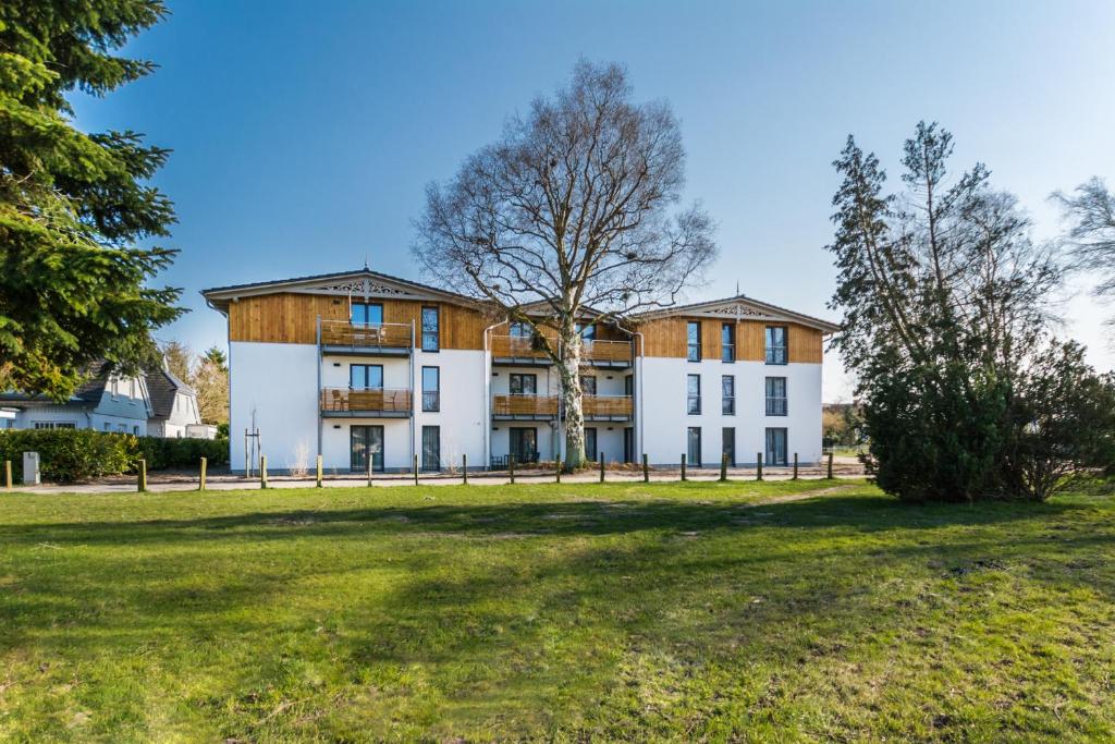 un grande edificio bianco con un albero di fronte di Apartmenthaus Am Park a Prerow