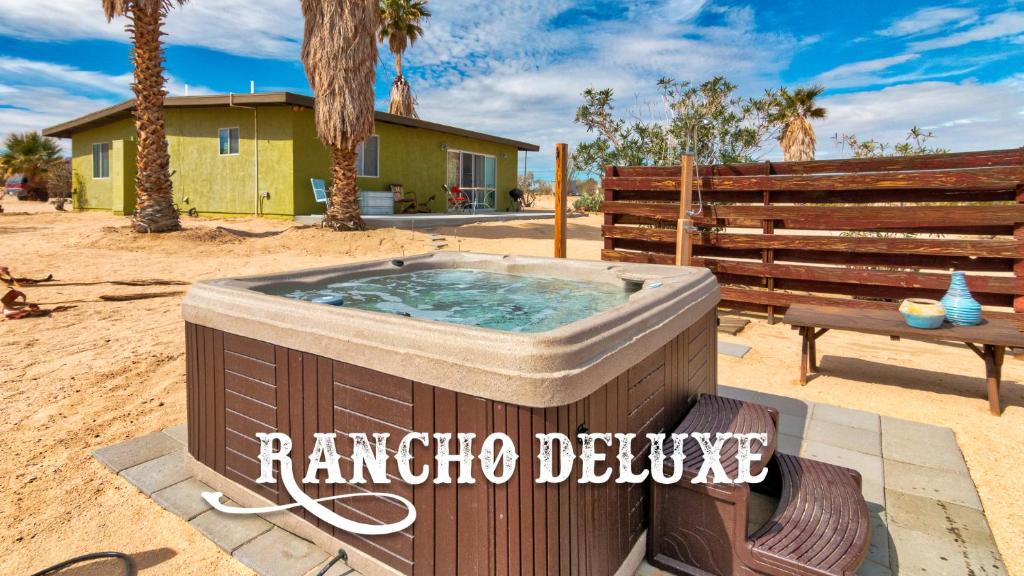 a hot tub in a yard with a bench and a house at Rancho Deluxe in Twentynine Palms