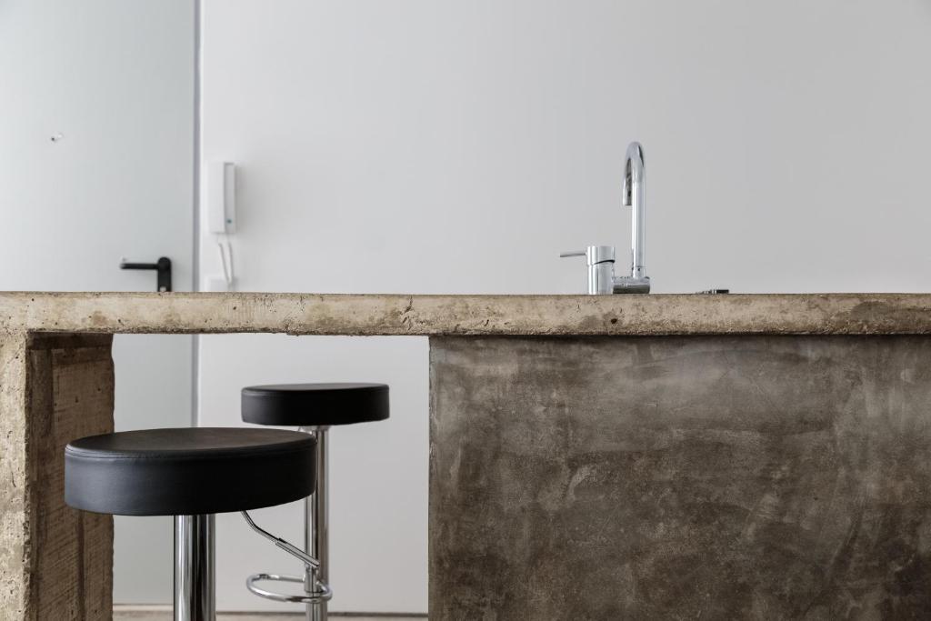 a bar with a black stool in front of a concrete counter at Fran Pacheco 39 (downtown apartment) in Setúbal