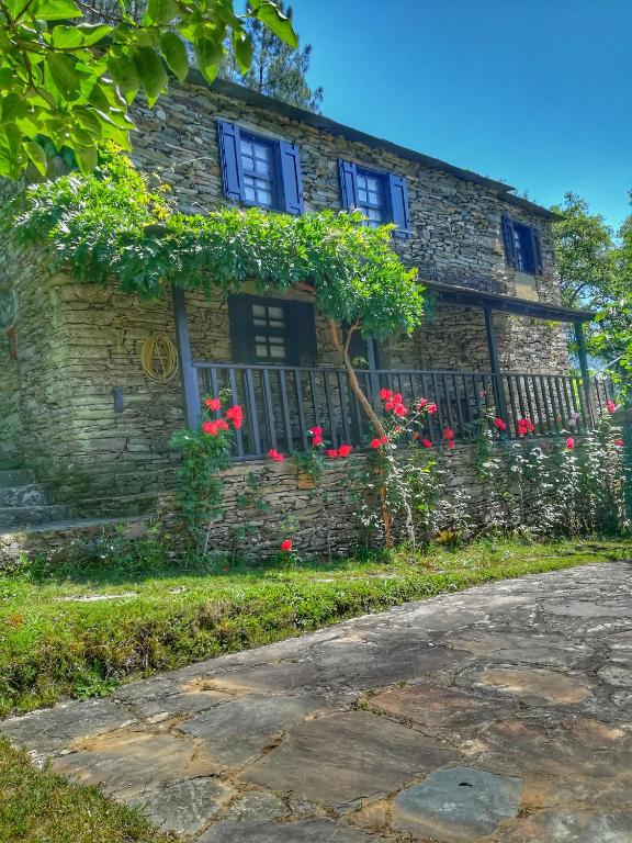 a stone house with flowers in front of it at Quinta da Recochina in Castro Daire