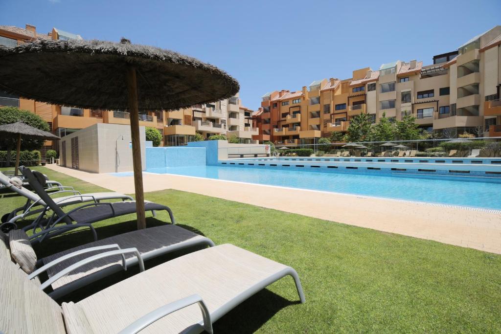 een groep stoelen en een parasol naast een zwembad bij Ribera del Marlin in Sotogrande