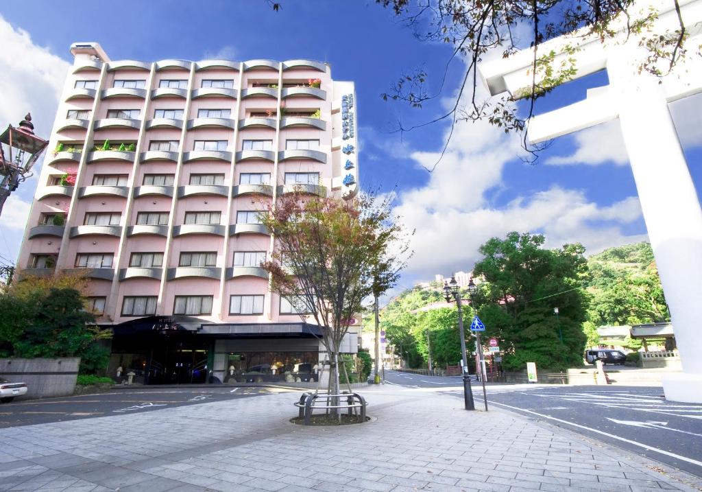 a building on a street with a tree in front of it at Hotel Fukiageso in Kagoshima