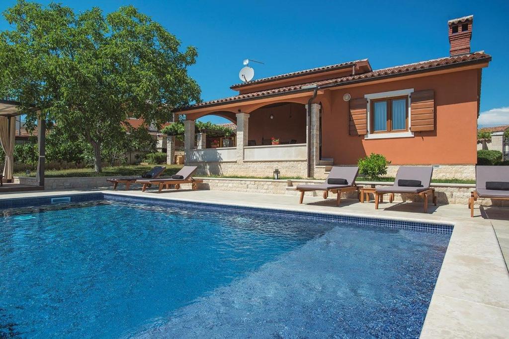 a swimming pool in front of a house at Villa Maria Betiga in Barbariga