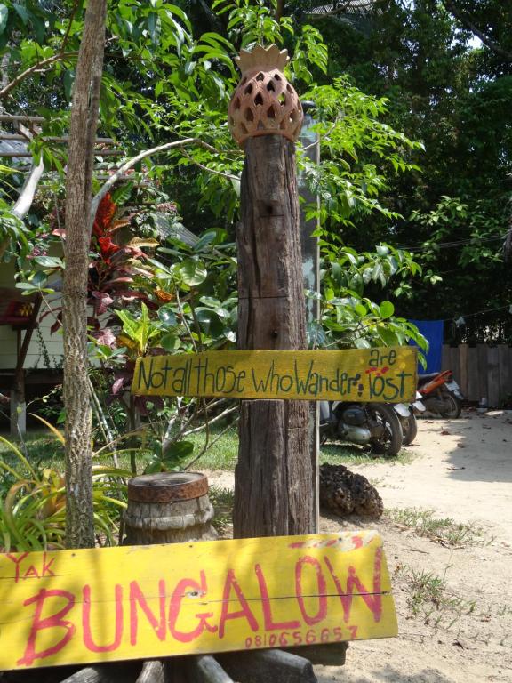 una señal en un poste de madera con una señal amarilla en Yak Bungalow, en Ko Chang