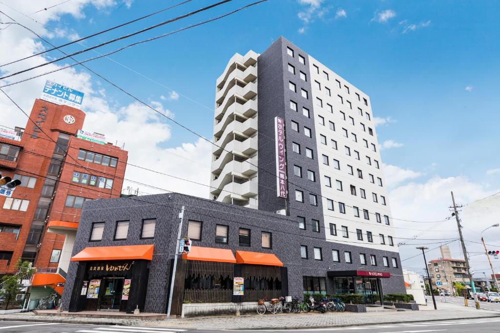 un edificio alto negro en una calle de la ciudad en Hotel Wing International Kumamoto Yatsushiro, en Yatsushiro