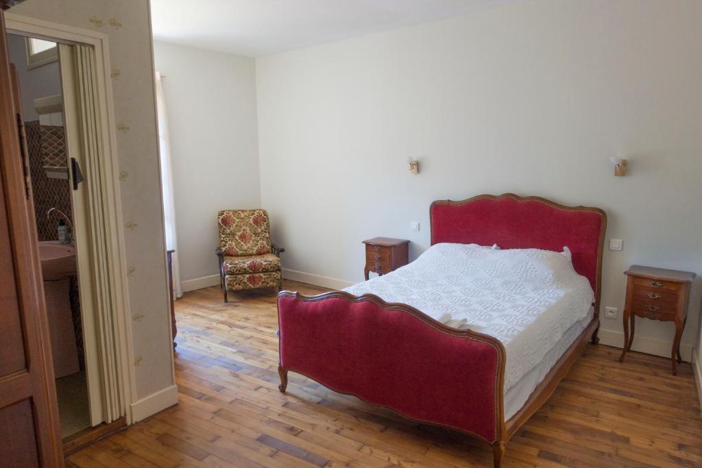 a bedroom with a red bed and a chair at Hotel Solomiac in Grand-Vabre