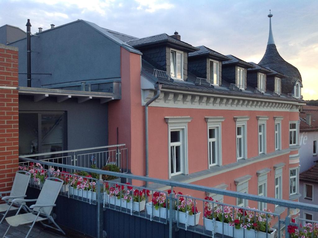 einen Balkon mit Stühlen und Blumen auf einem Gebäude in der Unterkunft Gästehaus "Rendezvous am Schlossplatz" in Coburg