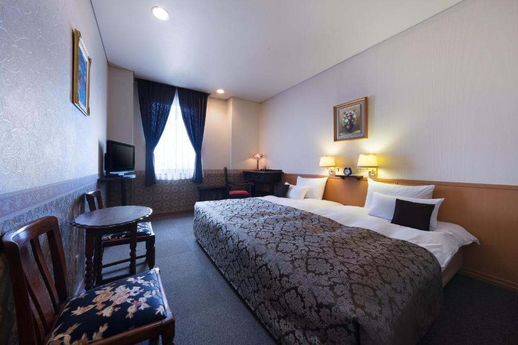 ein Hotelzimmer mit einem großen Bett und einem TV in der Unterkunft CHRES in Kōchi