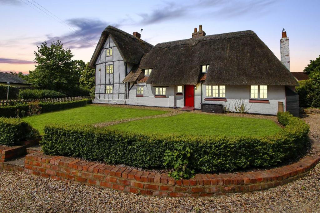an old white house with a thatched roof at Yew Tree Cottage in Moulsoe
