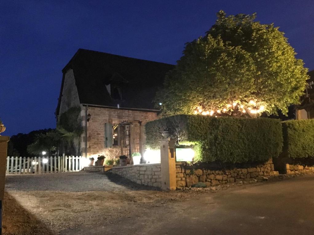 una casa con un muro di pietra e un albero di notte di Domaine Lacoste a Carsac-Aillac