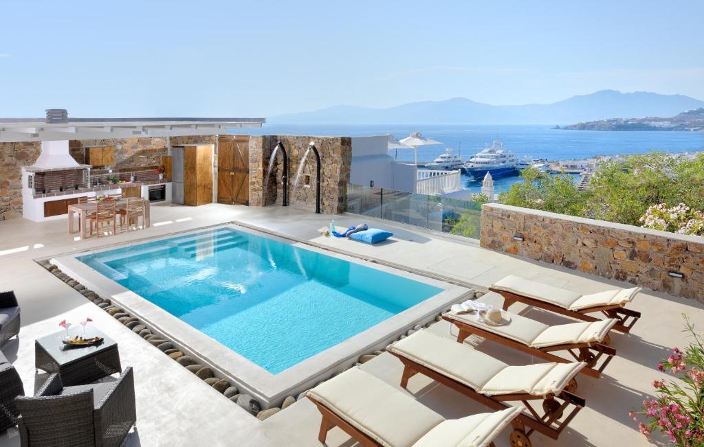 a villa with a swimming pool and a view of the ocean at Elegant Mykonos in Mýkonos City