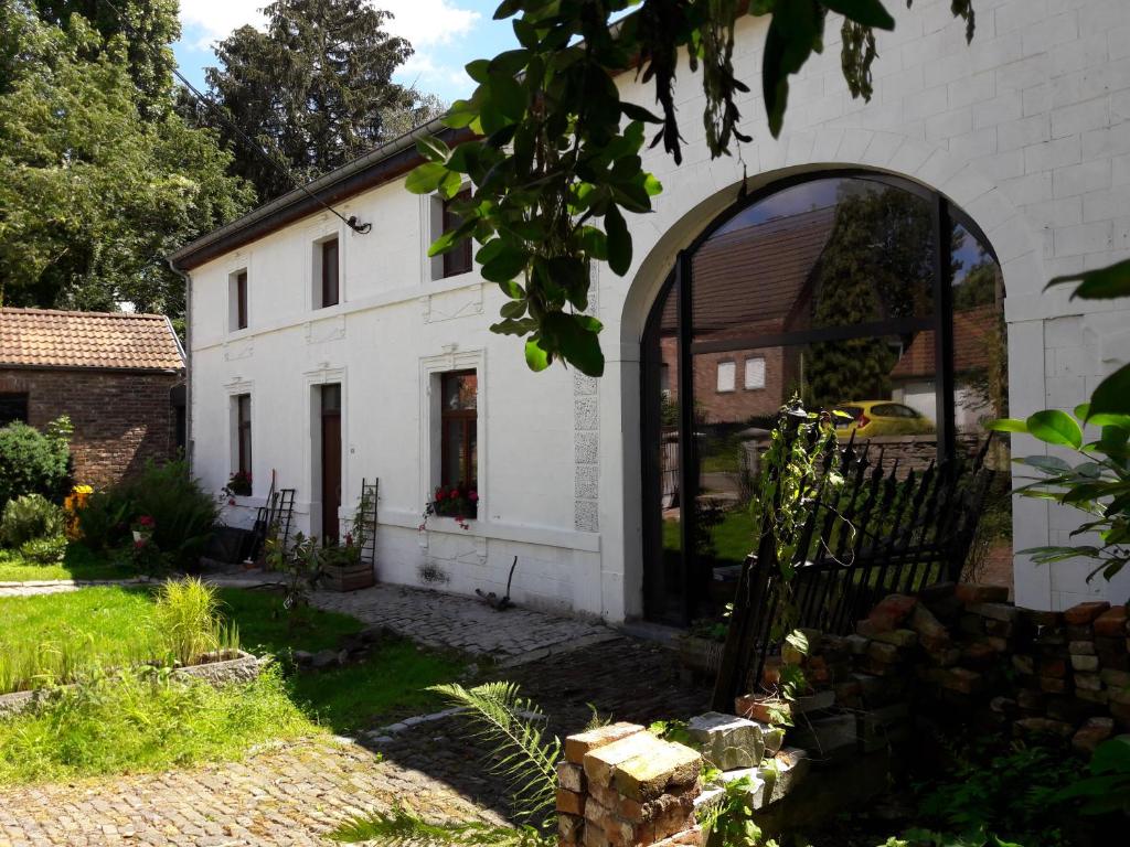 uma casa branca com uma arcada num quintal em La cave au chat'pitre 'Le Fenil' em Villers-le-Bouillet