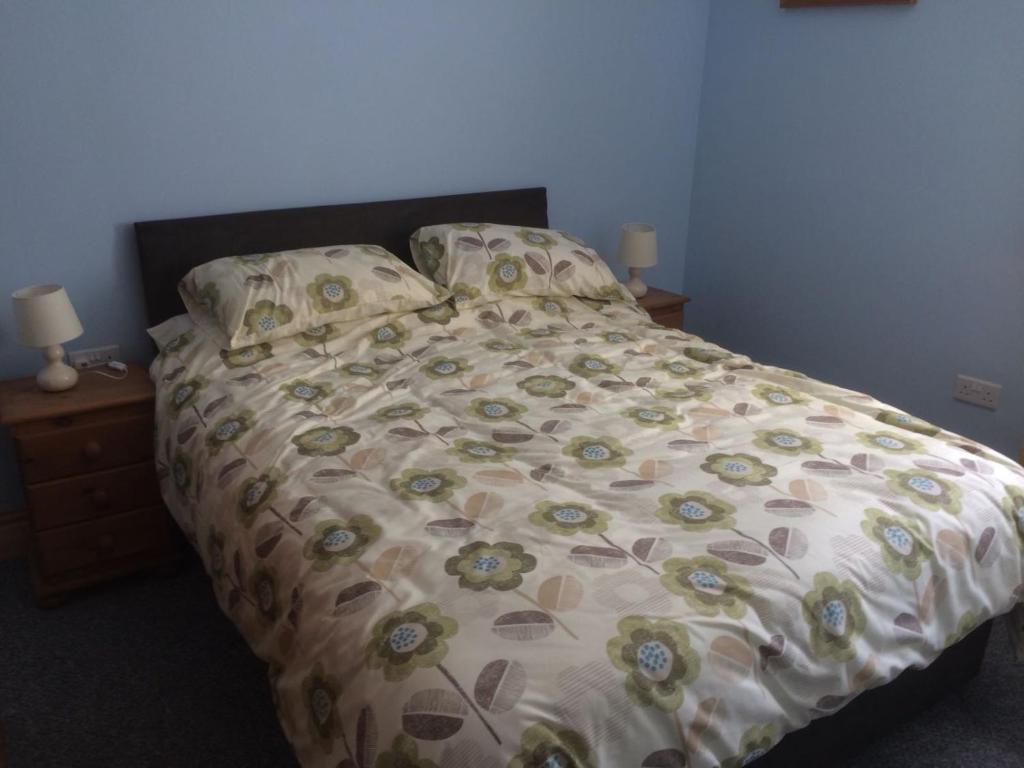 duże łóżko z kwiatową kołdrą i poduszkami w obiekcie Brentwood w mieście Beverley