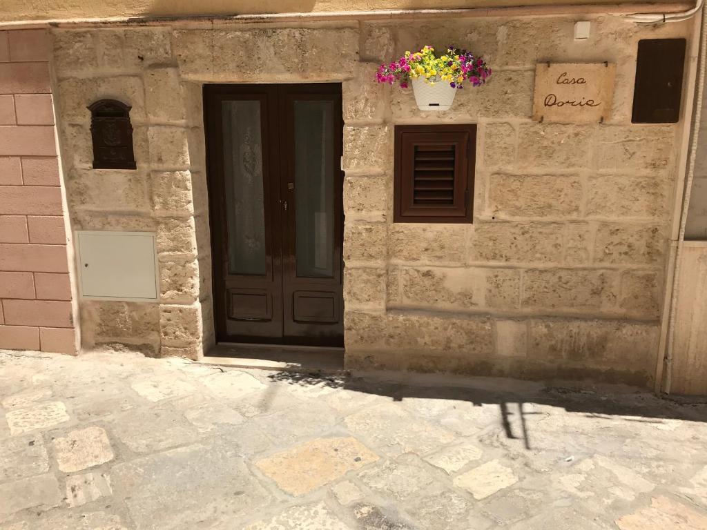- un bâtiment en pierre avec une porte ornée d'un pot de fleurs dans l'établissement Casa Doria, à Fasano
