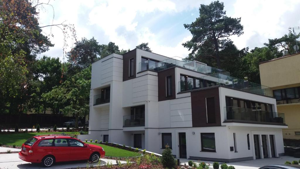 a red car parked in front of a white building at BALTIC PLAŻA przy plaży in Krynica Morska