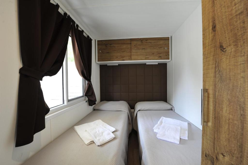 two beds in a small room with a window at Camping Bella Italia in Peschiera del Garda