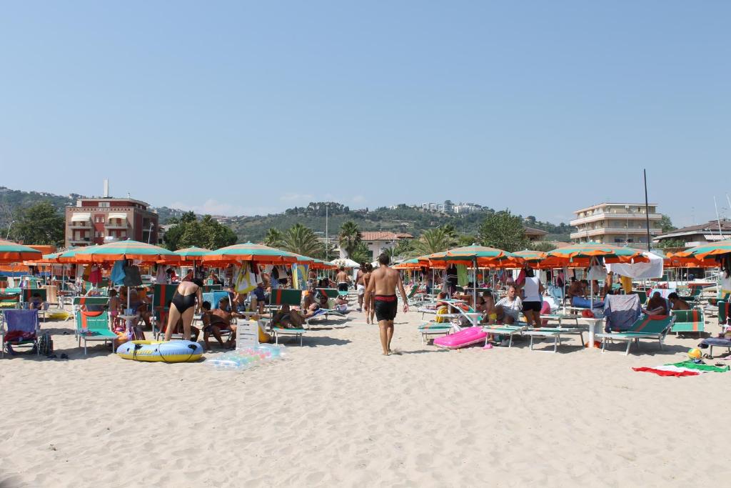 a group of people on a beach with umbrellas at Hotel Lidia in Alba Adriatica