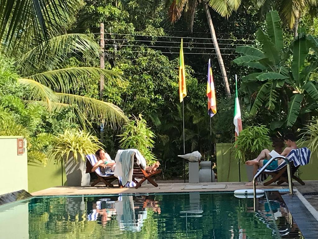 a group of people sitting next to a swimming pool at Hotel Heladiv in Anuradhapura