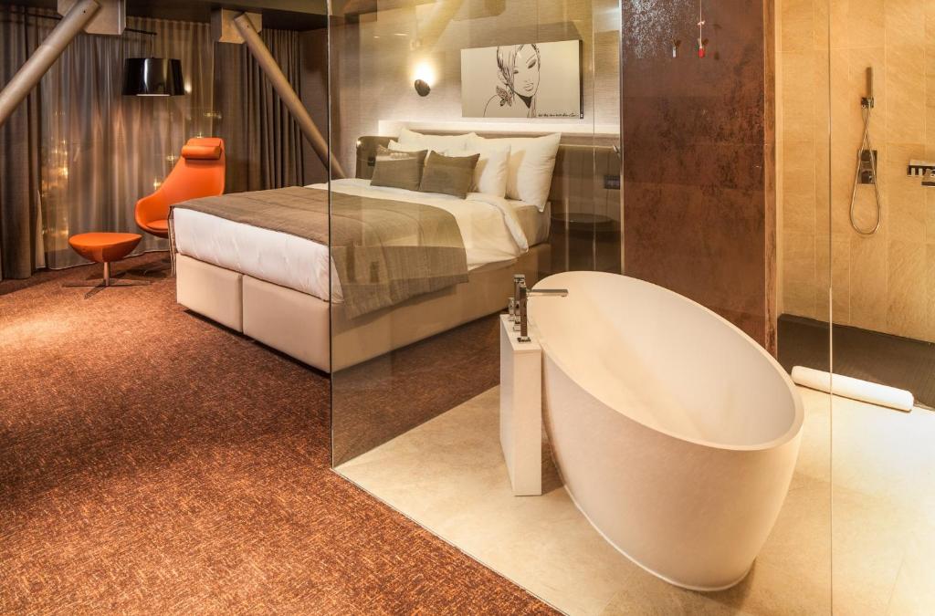 a bathroom with a bath tub next to a bed at Kronwell Brasov Hotel in Braşov