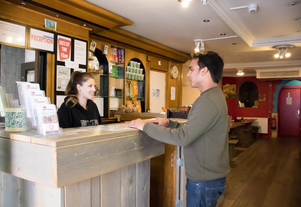 a man and a woman standing at a counter at Amsterdam Hostel Orfeo in Amsterdam