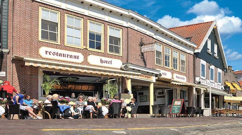 un grupo de personas sentadas fuera de un edificio en Hotel Cafe Restaurant Van Den Hogen en Volendam