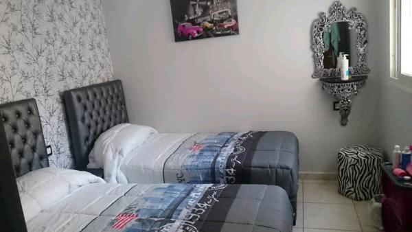 een slaapkamer met een bed en een spiegel aan de muur bij Jawharat Tetouan in Souani