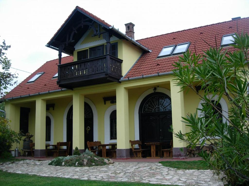 a yellow house with a balcony on top of it at Nitt Pince és Panzió in Kisharsány