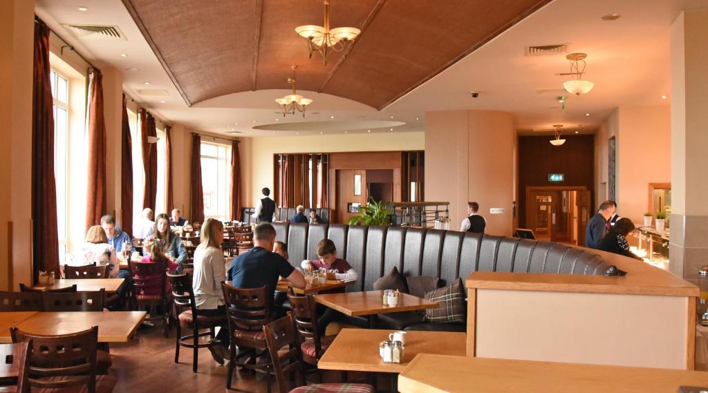 a restaurant with people sitting at tables in a restaurant at Portrush Atlantic Hotel in Portrush