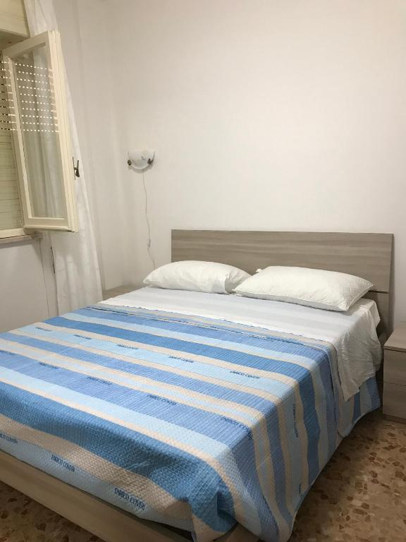 a bed with a blue and white striped blanket on it at Casa Vacanza Trabocco in Vasto