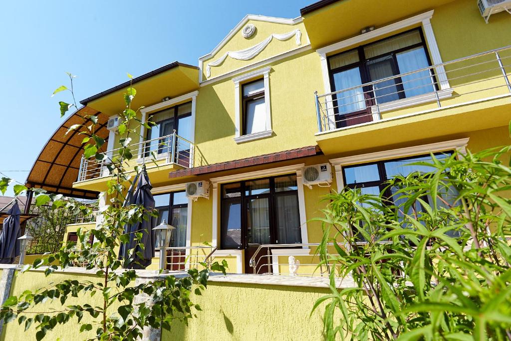 アドレルにあるГостевой дом Астраの黒窓と木々のある黄色い家