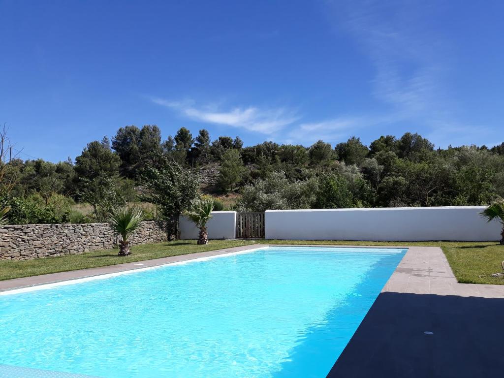 una piscina en un patio con una valla y árboles en location Phoebé dans la propriété Elaia, en Tourouzelle