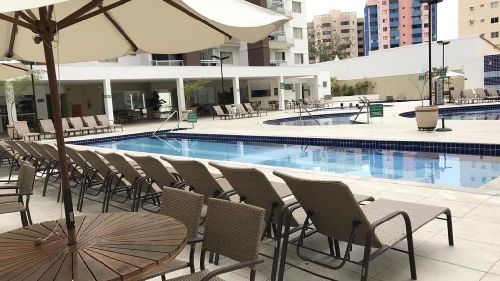 - Piscina con sillas, mesa y sombrilla en Casa da Madeira 1 OU 2 QUARTOS, en Caldas Novas