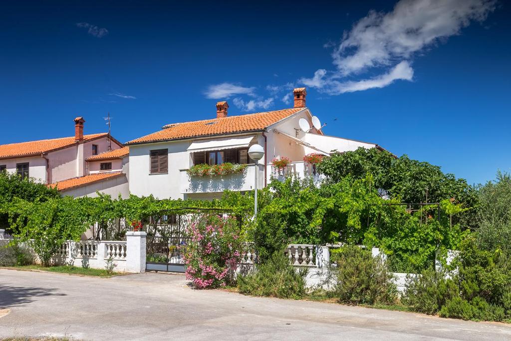 a white house with a white fence and plants at Apartman D&D, Dvorine 63 in Banjole