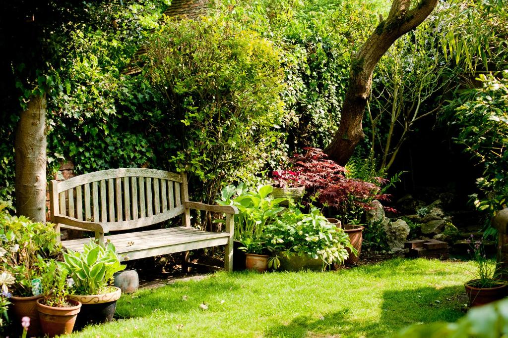 un banco de madera en un jardín con plantas en The Old Stables B&B, en Winslow