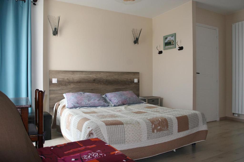 1 dormitorio con 1 cama con cabecero de madera en Les 3 Vallées, en Saint-Florent-le-Vieil