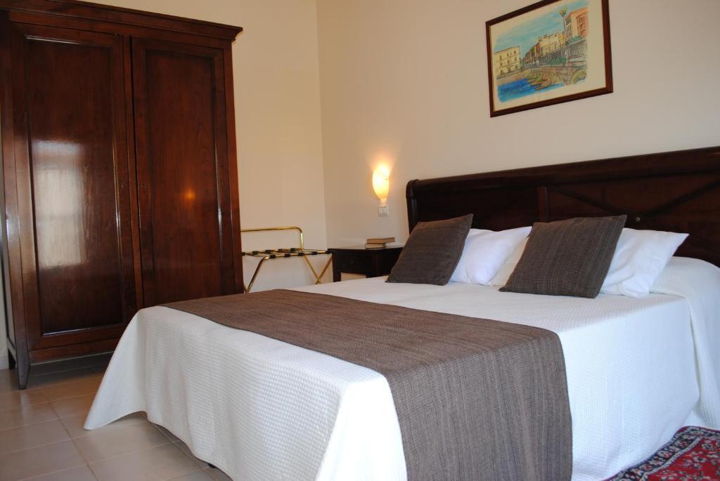 1 dormitorio con 1 cama con sábanas blancas y cabecero de madera en Hotel Park Siracusa Sicily en Siracusa