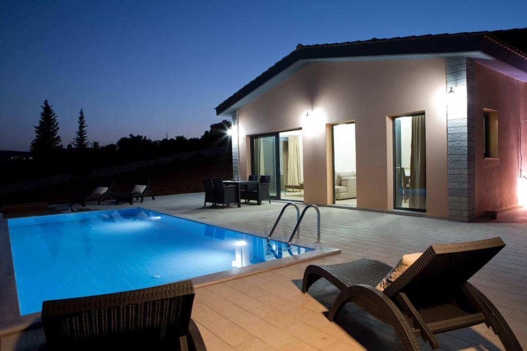 a swimming pool with chairs and a house at Nema Villa in Meganisi