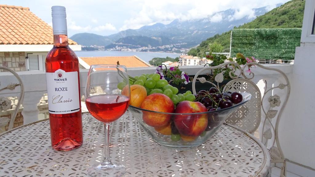 a glass of wine and a bowl of fruit on a table at Apartments - IRINA in Sveti Stefan