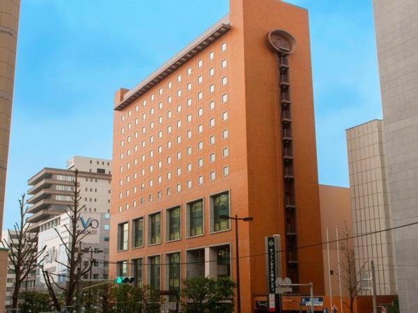 un edificio alto de color naranja en medio de una ciudad en Sutton Hotel Hakata City, en Fukuoka