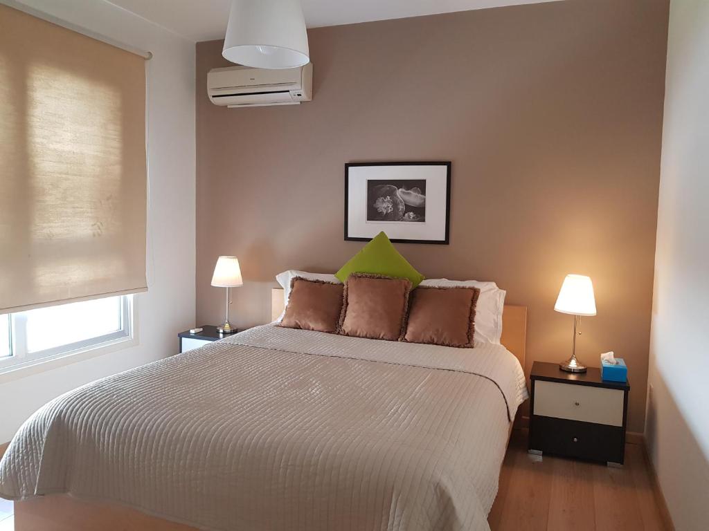 um quarto com uma cama grande e uma almofada verde em Achillion Gardens, near UNIC By 'Flats Nicosia' em Nicósia