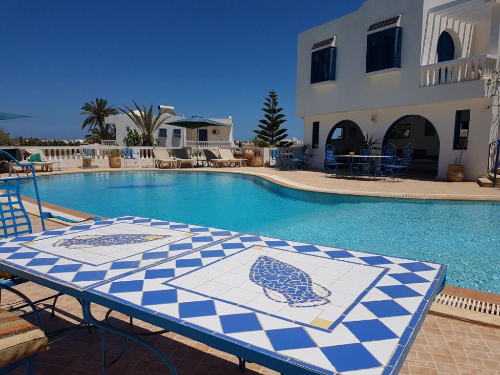 a swimming pool with a table with a blue and white at Dar Amphora Menzel in Midoun