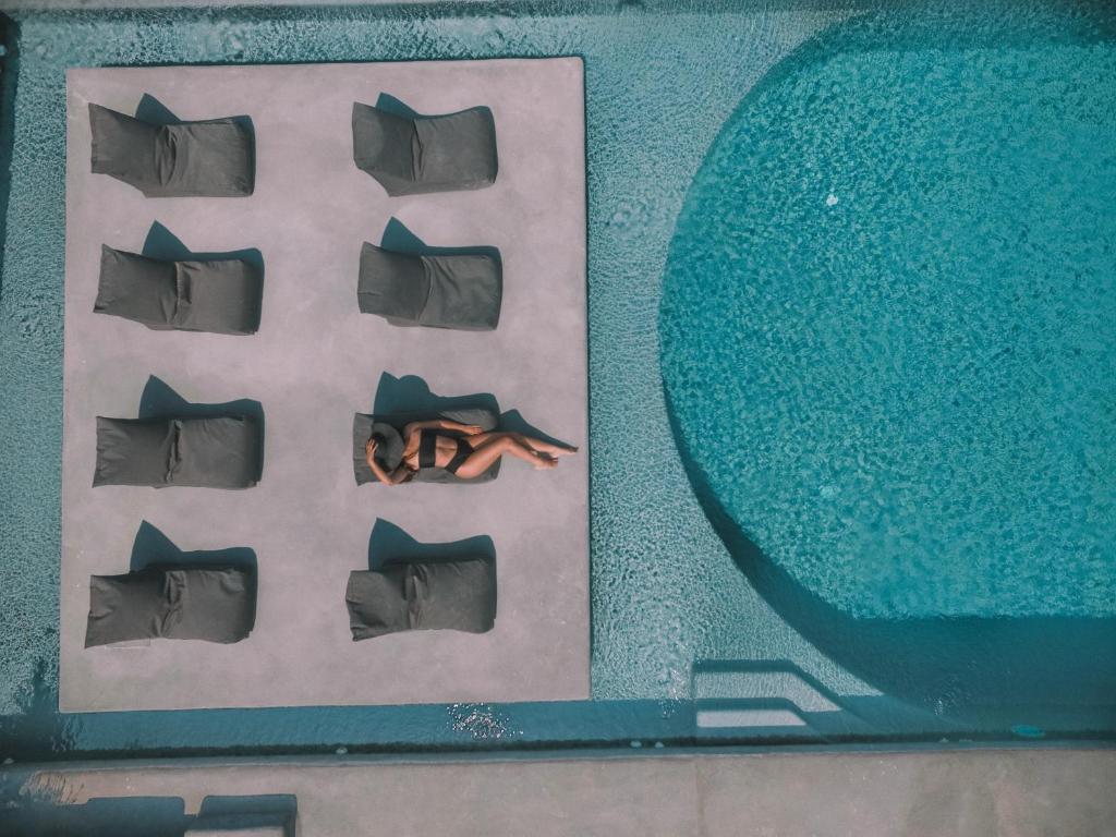 a picture of a pool with a person laying next to it at Santorini Villas in Vourvoúlos