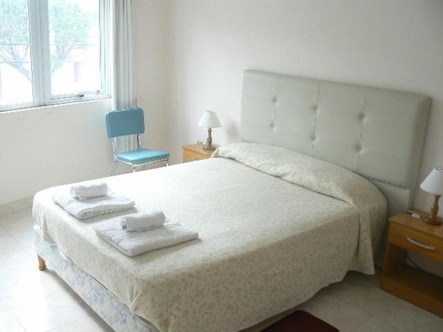 1 dormitorio con 1 cama grande y 1 silla azul en Departamentos Santa Monica en Puerto Madryn