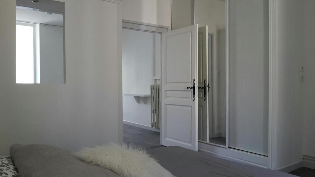 a white room with a couch and a mirror at Appartement PAP2S in Millau